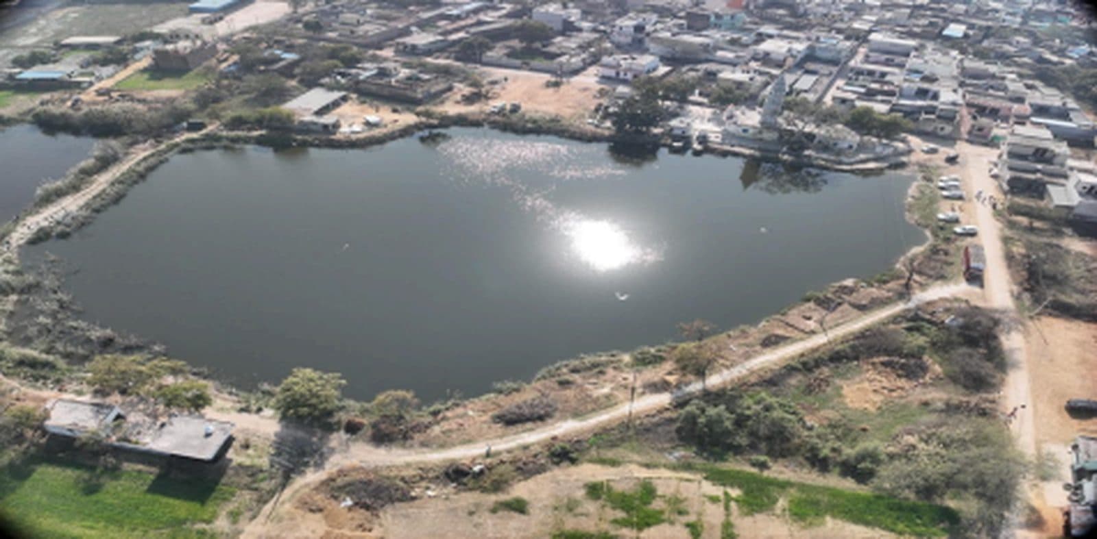 Aerial view of Mankrola Pond before interventions, 27 January 2025 — bare, dusty edges and murky water