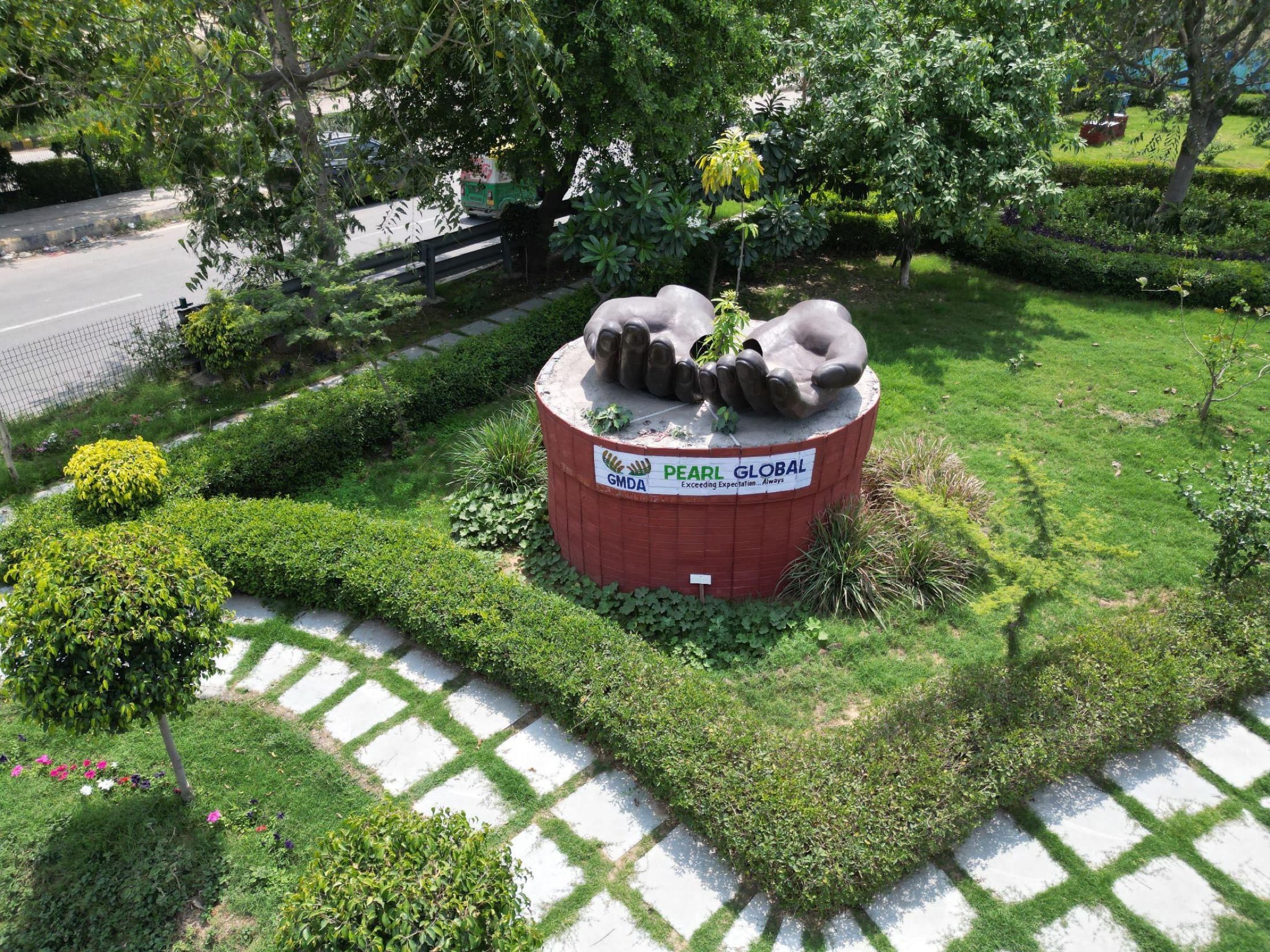 A sculpture of two hands cradling a sapling, jointly branded by GMDA and Pearl Global, at the centre of the site